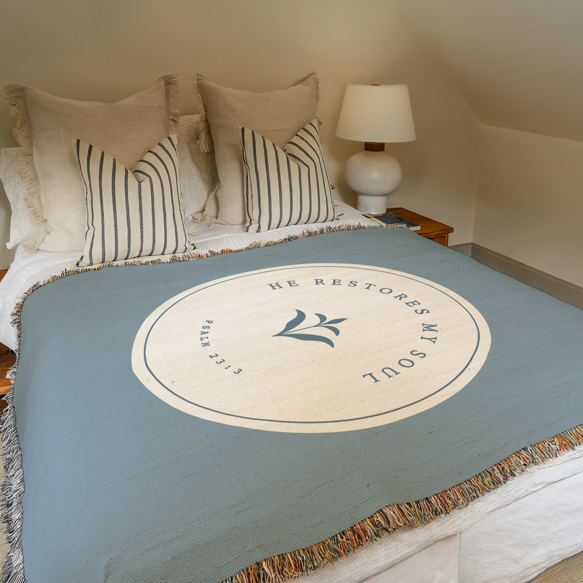 Bed with a blue throw blanket featuring a circular design and text, in a bedroom setting.