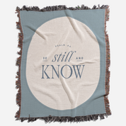 Blanket with 'Be still and know' text on a white background