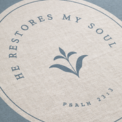Circular design with text 'He restores my soul' from Psalm 23:3 on a textured background.