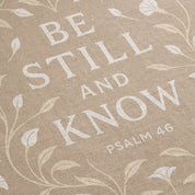 Cream-colored woven blanket with the phrase “Be still and know” from Psalm 46, made of 100% cotton with fringe; a peaceful Christian gift for nurseries or weddings.