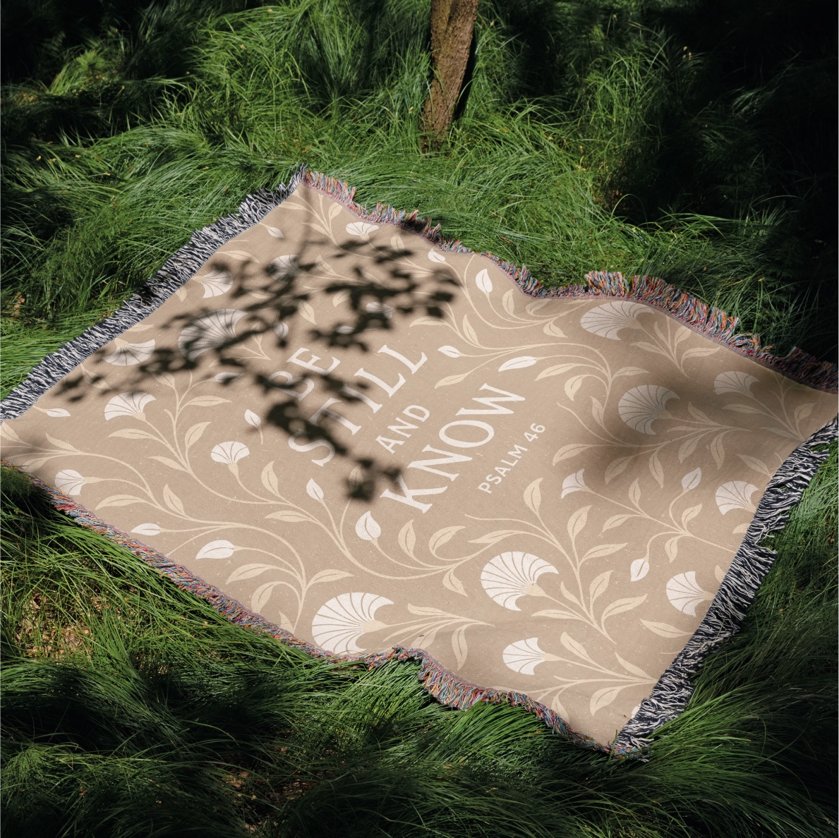 Cream-colored woven blanket with the phrase “Be still and know” from Psalm 46, made of 100% cotton with fringe; a peaceful Christian gift for nurseries or weddings.