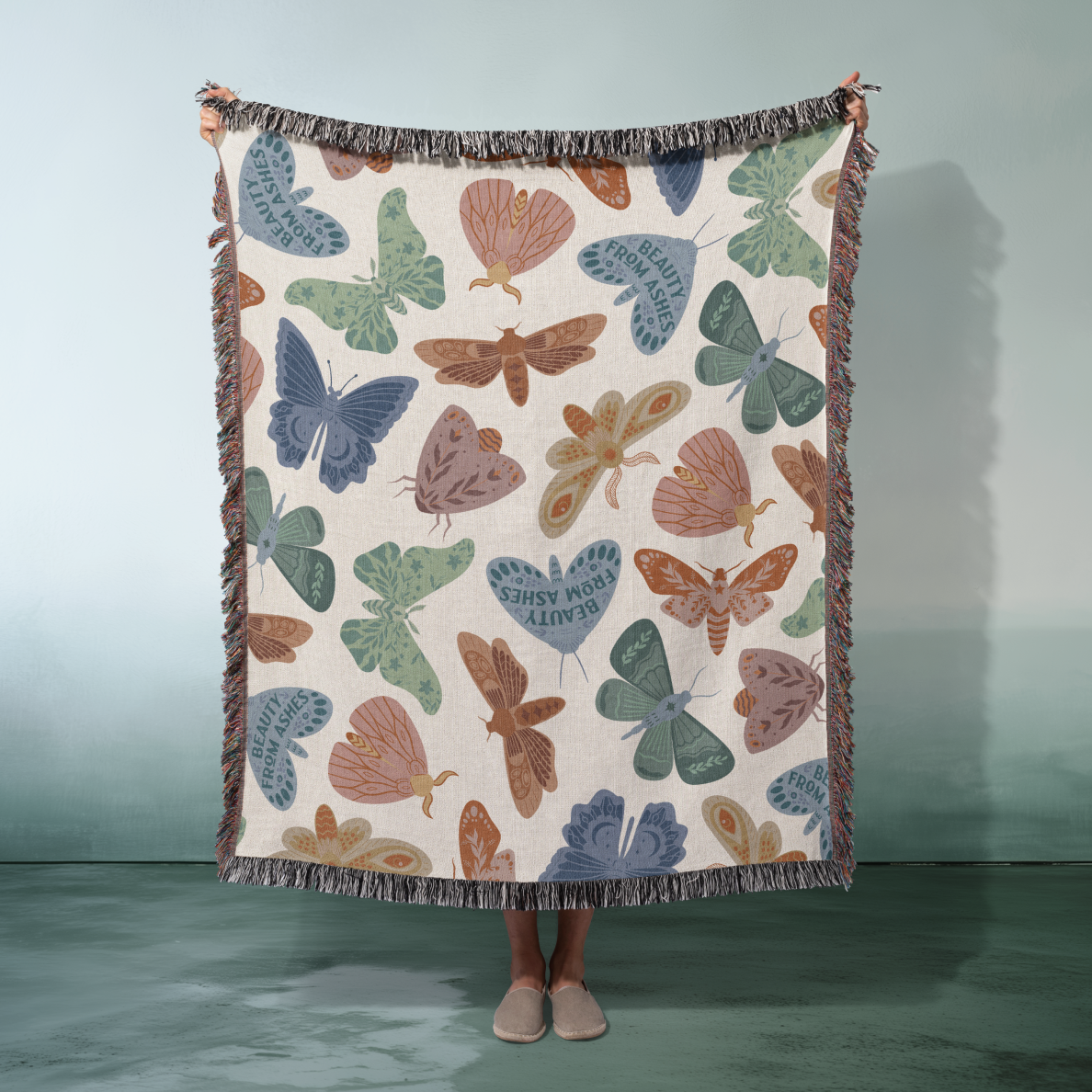 Blanket with butterfly pattern held by a person against a light blue background