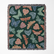 Faith-inspired woven blanket with hand-drawn butterflies and moths on a deep background, made from 100% cotton with colorful fringed edges—Christian home decor.