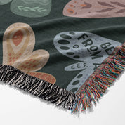 Faith-inspired woven blanket with hand-drawn butterflies and moths on a deep background, made from 100% cotton with colorful fringed edges—Christian home decor.