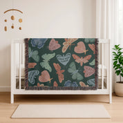 Faith-inspired woven blanket with hand-drawn butterflies and moths on a deep background, made from 100% cotton with colorful fringed edges—Christian home decor.