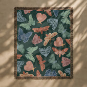 Faith-inspired woven blanket with hand-drawn butterflies and moths on a deep background, made from 100% cotton with colorful fringed edges—Christian home decor.