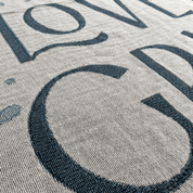 Close-up of a woven textile with large dark navy lettering on a light beige background.