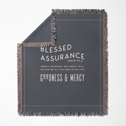 Gray blanket with text 'Blessed Assurance' and 'Goodness & Mercy' on a white background