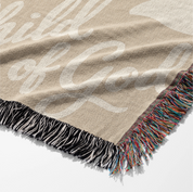 Neutral-toned woven blanket with “Child of God” text and delicate cream foliage design; 100% cotton with fringe, perfect for nurseries, baby gifts, or faith-inspired décor.