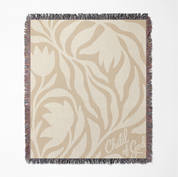 Neutral-toned woven blanket with “Child of God” text and delicate cream foliage design; 100% cotton with fringe, perfect for nurseries, baby gifts, or faith-inspired décor.