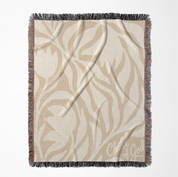 Neutral-toned woven blanket with “Child of God” text and delicate cream foliage design; 100% cotton with fringe, perfect for nurseries, baby gifts, or faith-inspired décor.