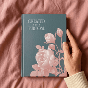 Woman holding Created for a Purpose christian journal with blush rose cover against pink background