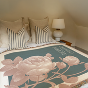 Floral blanket with text on a bed in a bedroom setting