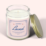White jar candle labeled “Divinely Loved” with a gold lid. Cinnamon chai scent and Christian message—warm, comforting gift rooted in God’s love.