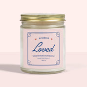 White jar candle labeled “Divinely Loved” with a gold lid. Cinnamon chai scent and Christian message—warm, comforting gift rooted in God’s love.