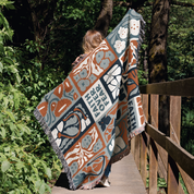 Person walking on a wooden bridge with a colorful patterned blanket draped over their shoulders.