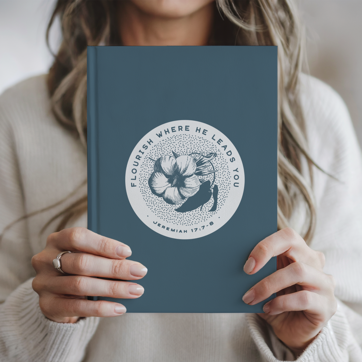 Person holding a blue book with a floral design and text