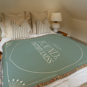 Green blanket with 'Found Fullness' text on a bed in a bedroom setting.