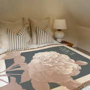 Bed with floral blanket and striped pillows in a bedroom setting.