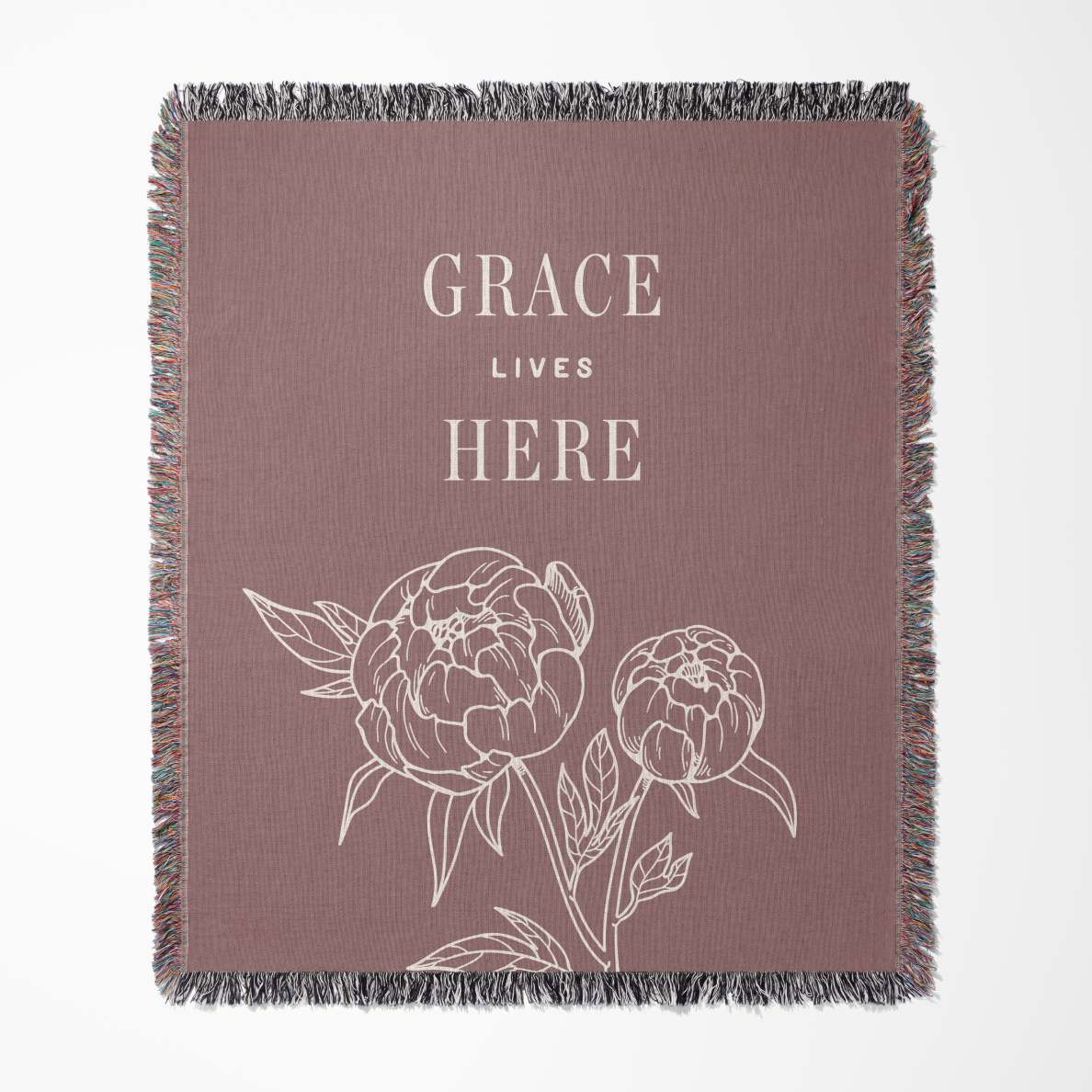 Blanket with floral design and 'Grace Lives Here' text on a plain background