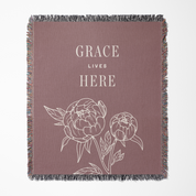 Blanket with floral design and 'Grace Lives Here' text on a plain background