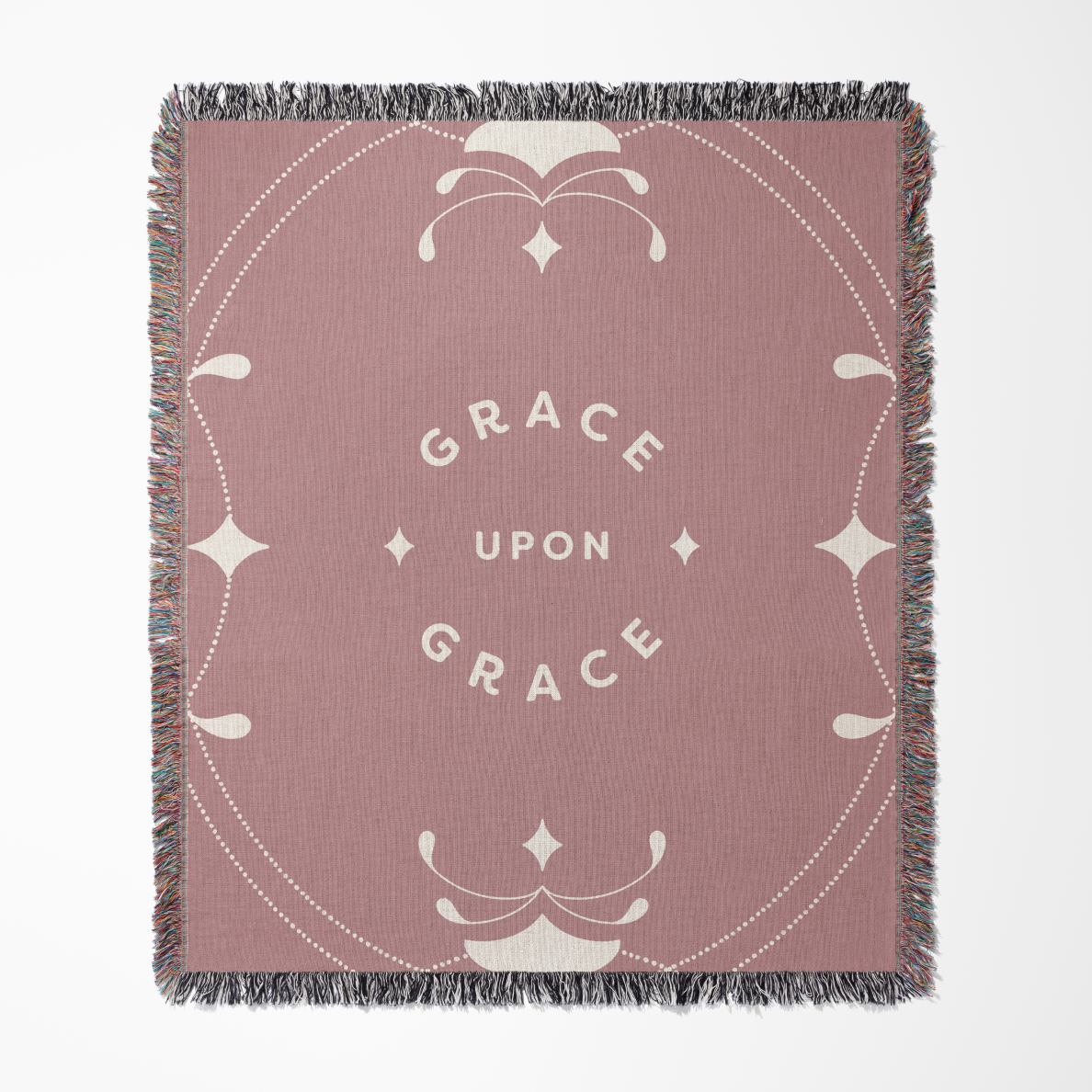 Pink blanket with 'Grace Upon Grace' text and decorative elements on a white background