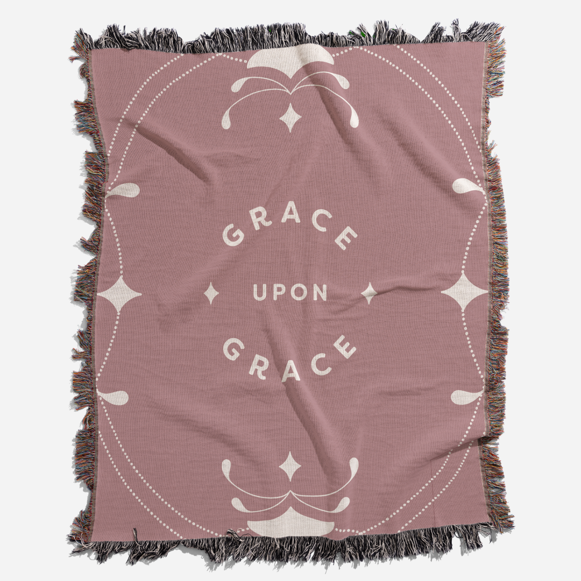 Pink throw blanket with 'Grace Upon Grace' text and decorative patterns on a white background