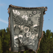 Floral patterned blanket with text against a blue sky and green trees background
