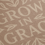 Neutral-toned woven blanket with the phrase "Grow in Grace" surrounded by elegant floral design; made from 100% cotton with fringe, perfect Christian gift or decor.