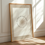 Framed artwork with text and sun design on a wall with sunlight casting shadows.