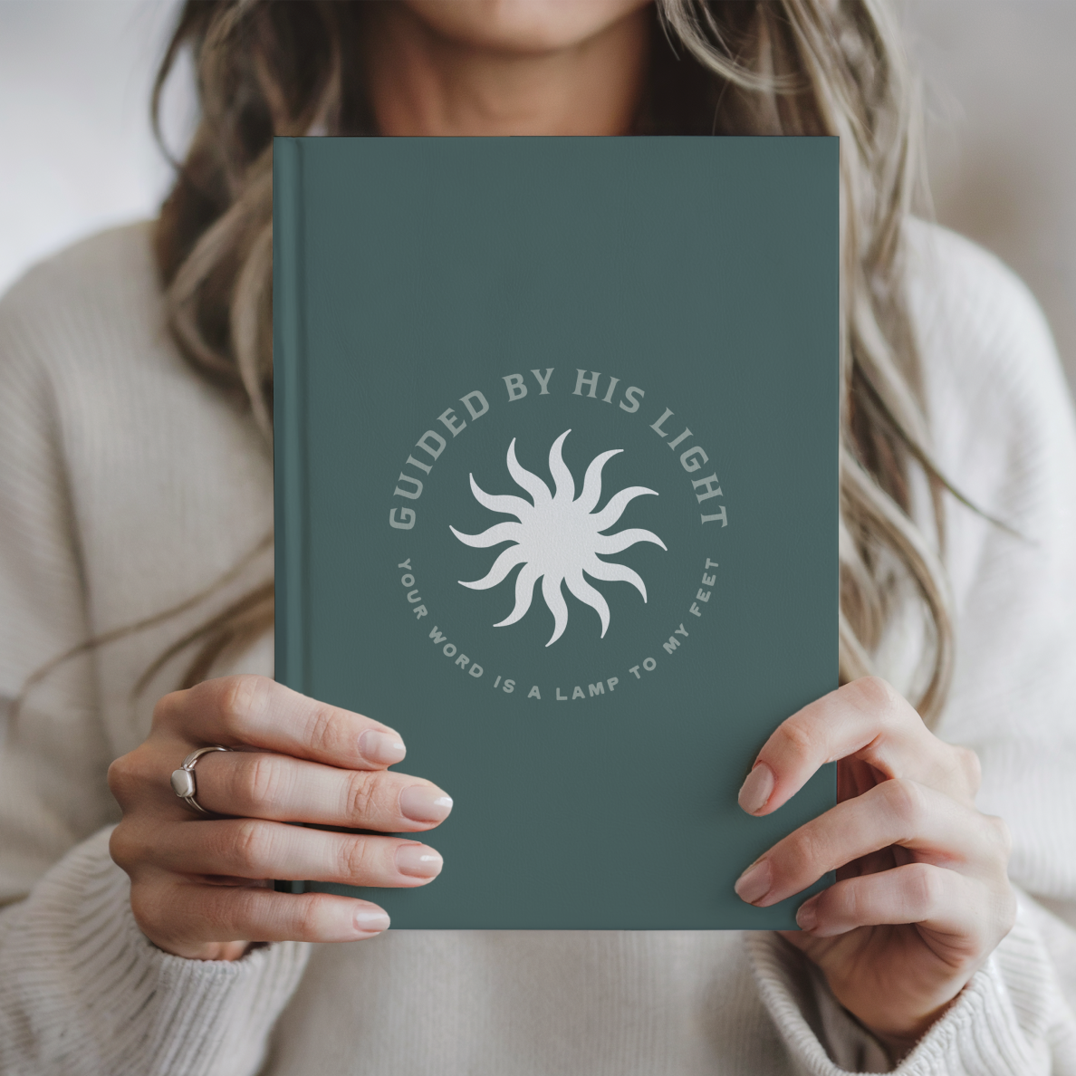 Person holding a green notebook with a sun design and text
