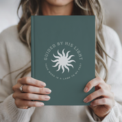 Person holding a green notebook with a sun design and text