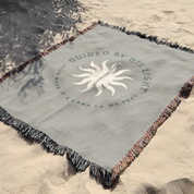 Blanket with text and sun design on sand