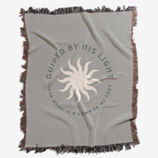 Gray blanket with sun design and text 'Guided by His Light' on a white background