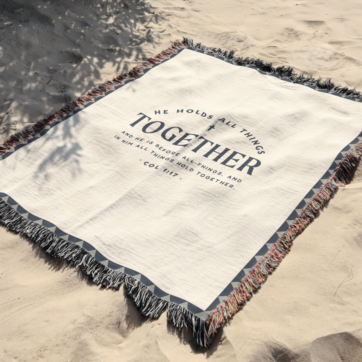 Blanket with 'He holds all things together' text on a sandy background