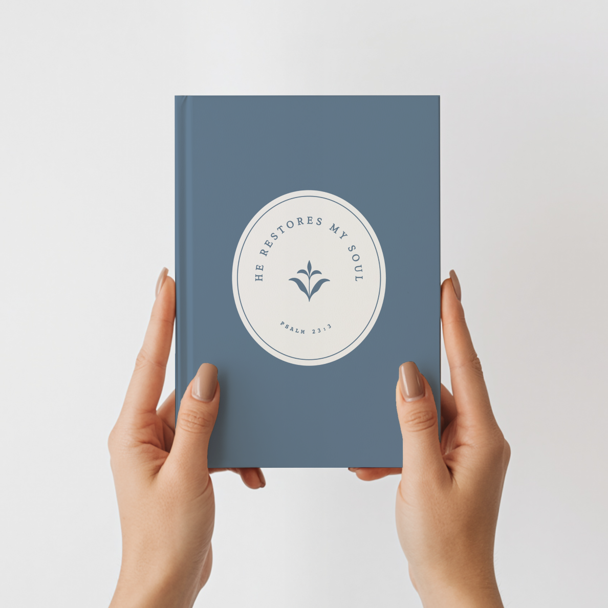 Blue book held by hands with a white emblem on a light gray background