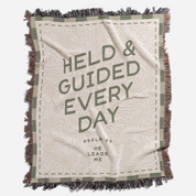Blanket with text 'HELD & GUIDED EVERY DAY' and 'PSALM 23 HE LEADS ME' on a white background