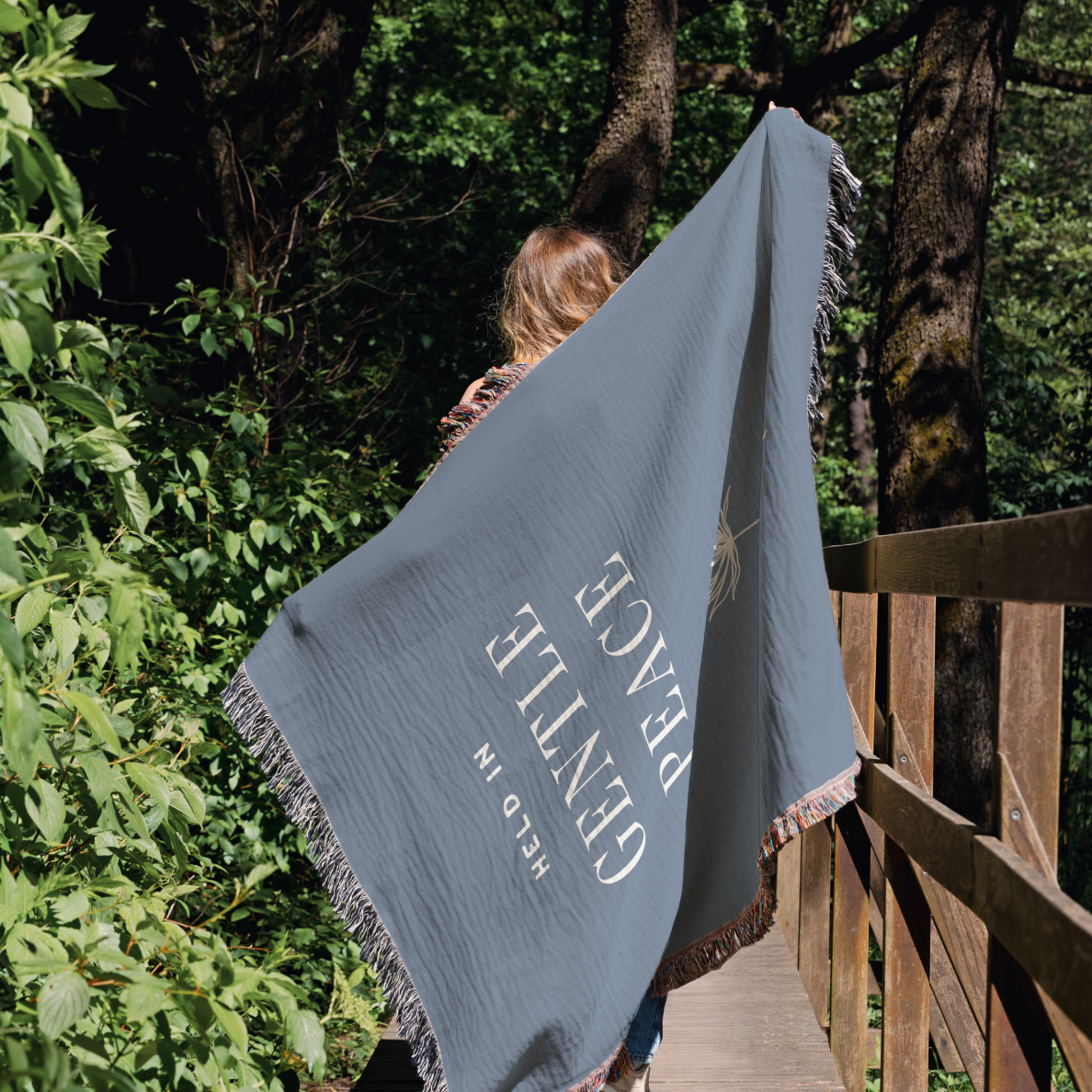 Person holding a blue blanket with text in a forest setting