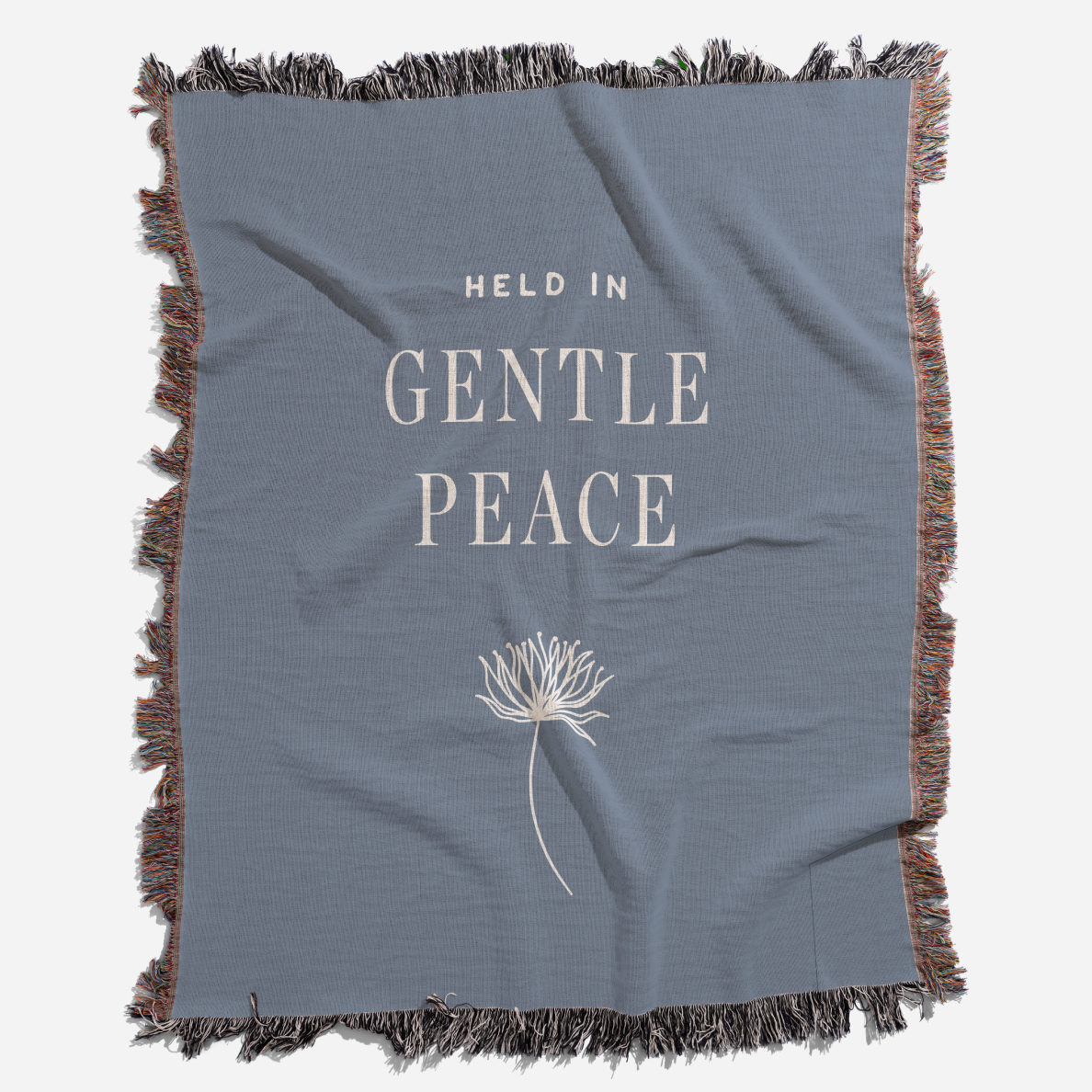 Blue blanket with 'Held in Gentle Peace' text and a dandelion graphic on a white background