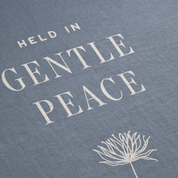 Text 'HELD IN GENTLE PEACE' on a textured blue background with a white flower illustration.