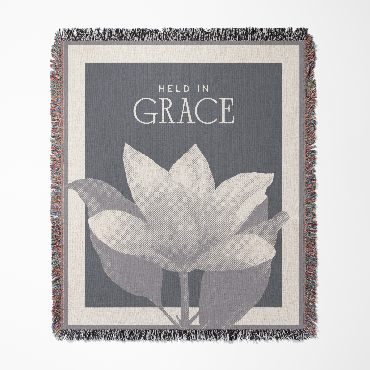 Blanket with floral design and 'Held in Grace' text on a gray background