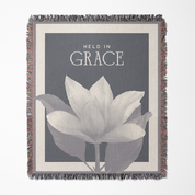 Blanket with floral design and 'Held in Grace' text on a gray background