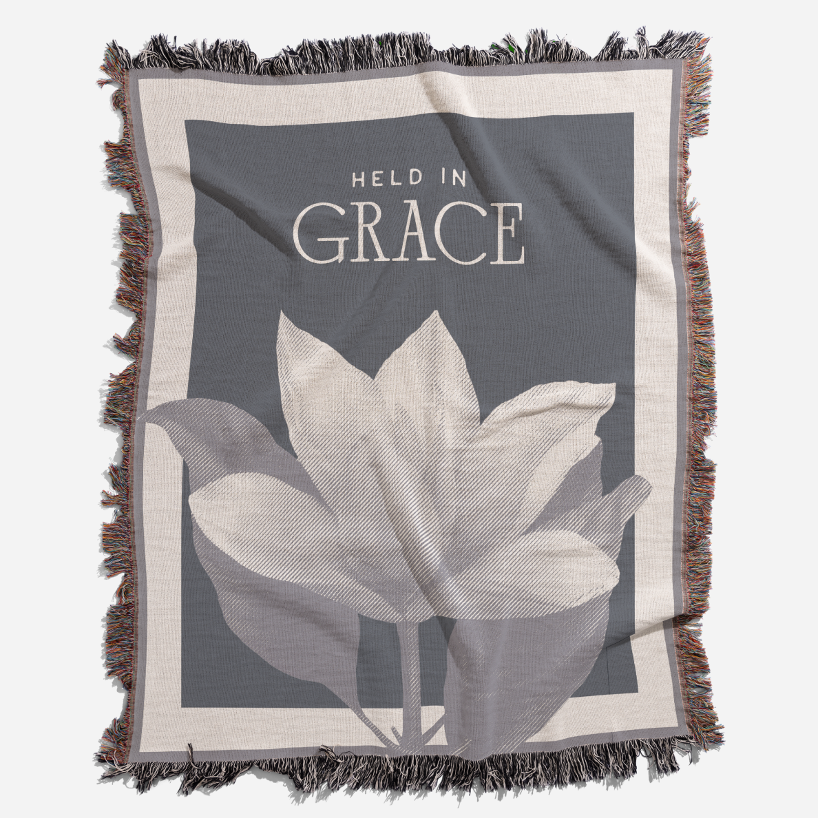Blanket with floral design and 'Held in Grace' text on a gray background