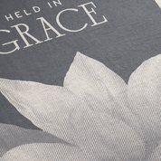 Text 'HELD IN GRACE' on a textured gray background