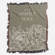 Olive green blanket with floral design and 'Held in Perfect Peace' text on a white background