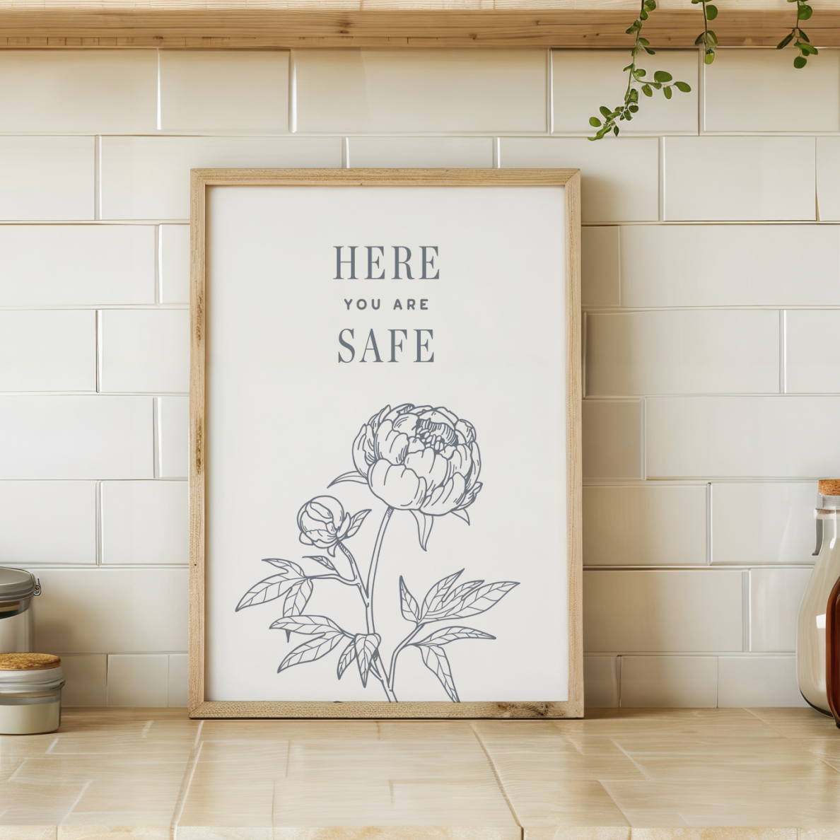 Framed artwork with floral design and text 'HERE YOU ARE SAFE' on a kitchen wall.