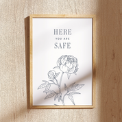 Framed artwork with floral design and 'Here You Are Safe' text on a textured wall.