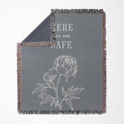 Gray blanket with floral design and 'Here You Are Safe' text on a white background