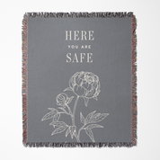 Gray blanket with floral design and 'Here You Are Safe' text on a white background