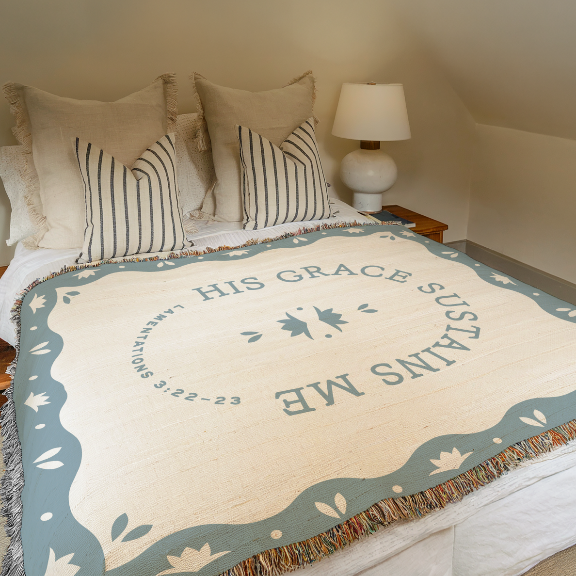 Blanket with 'His Grace Sustains Me' text on a bed in a bedroom setting